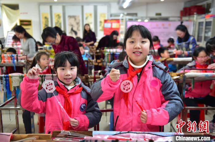 圖為小學生展示繡制好的2022年北京冬奧會吉祥物“冰墩墩”形象?！∮髟屏?攝