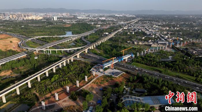 航拍正在建設(shè)的跨越成都繞城高速公路連續(xù)梁施工現(xiàn)場，旁邊依次為已運(yùn)營的成渝高速鐵路和機(jī)場高速公路?！⒅铱?攝