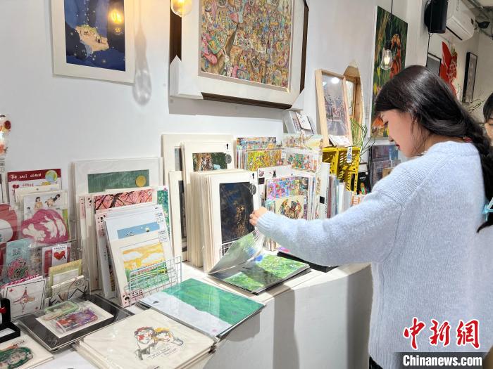 圖為藝術(shù)品商店內(nèi)，顧客挑選插畫作品?！＄婌?攝