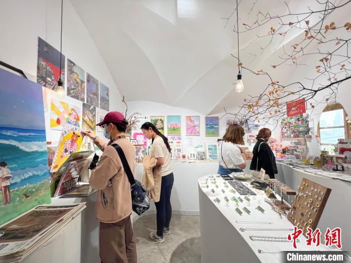 圖為藝術(shù)品商店內(nèi)，顧客挑選插畫作品?！＄婌?攝