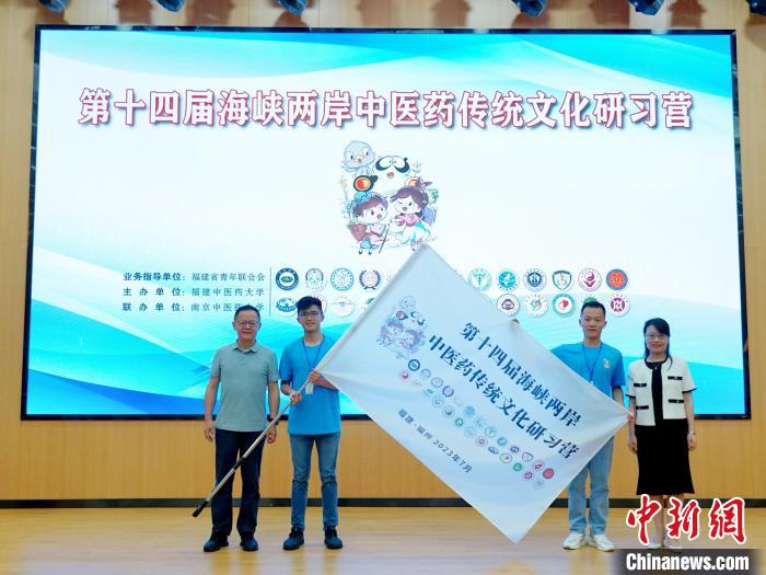 共青團(tuán)福建省委副書記吳雪(右一)、福建中醫(yī)藥大學(xué)黨委副書記林羽(左一)為兩岸學(xué)生代表頒授營旗?！≡S燁婷 攝