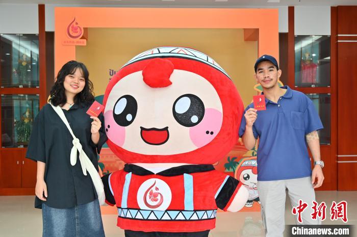 圖為泰國留學(xué)生手持獻血證與人偶合影?！∮峋?攝
