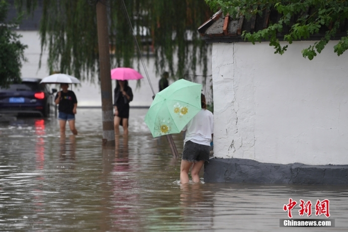 7月31日，市民行走在雨中的北京房山區(qū)瓦窯頭村。北京市氣象臺當日10時發(fā)布分區(qū)域暴雨紅色預(yù)警信號。北京市水文總站發(fā)布洪水紅色預(yù)警，預(yù)計當日12時至14時，房山區(qū)大石河流域?qū)⒊霈F(xiàn)紅色預(yù)警標準洪水。<a target='_blank' href='/'><p  align=