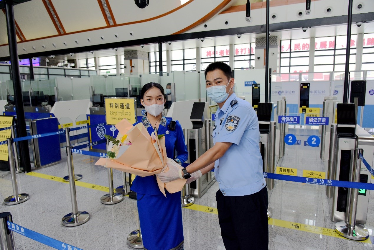 磨憨出入境邊防檢查站民警為中老鐵路第100萬(wàn)名出入境旅客，D888次國(guó)際旅客列車?yán)蠐爰藙?wù)員森達(dá)拉·妮緹婭（Sengdala Nitiya），送上鮮花。黃遠(yuǎn)飛 攝