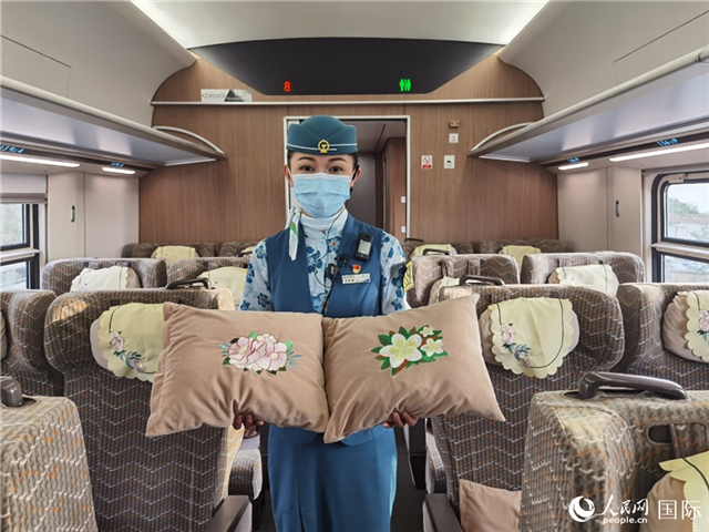 趙瑩靜展示中老鐵路國際旅客列車里帶有中國牡丹花和老撾占巴花刺繡圖案的靠墊。人民網(wǎng)記者 杜明明攝