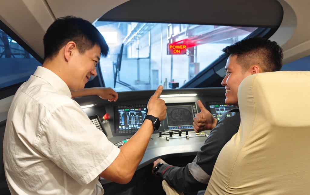 8月25日，在印度尼西亞萬隆的雅萬高鐵德卡魯爾動車所內(nèi)，中國師傅穆振（左）在向印尼火車司機塞蒂亞萬講解動車組出庫前的上電作業(yè)。