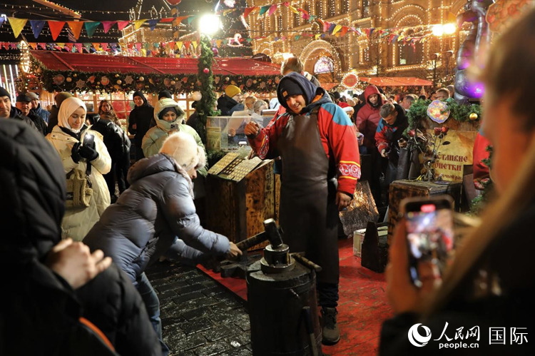 游客在新年集市上體驗制作紀(jì)念幣。人民網(wǎng)記者 隋鑫攝