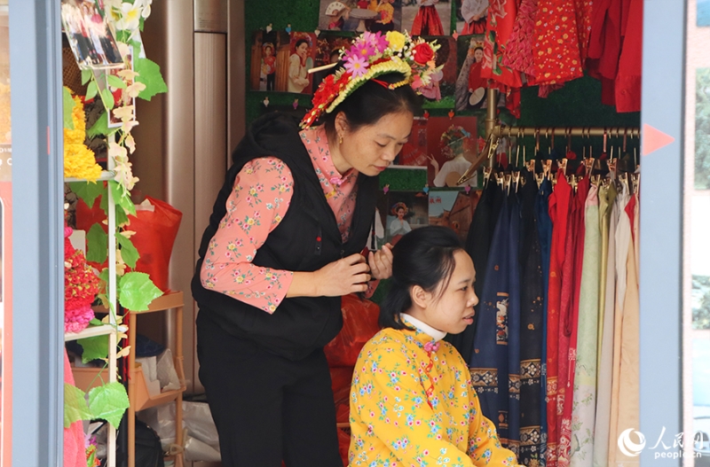泉州府文廟附近，一名店主正為過(guò)路游客梳理頭發(fā)以佩戴“簪花圍”。人民網(wǎng) 黃東儀攝