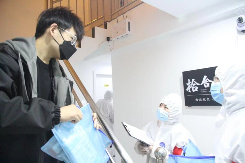 社區(qū)工作人員和志愿者身穿防護服上門送馬應龍大健康防疫包。徐帥攝