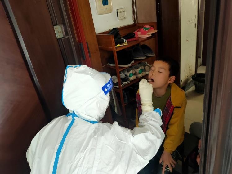 醫(yī)務(wù)工作者為封控區(qū)的居民上門采樣核酸。單位供圖