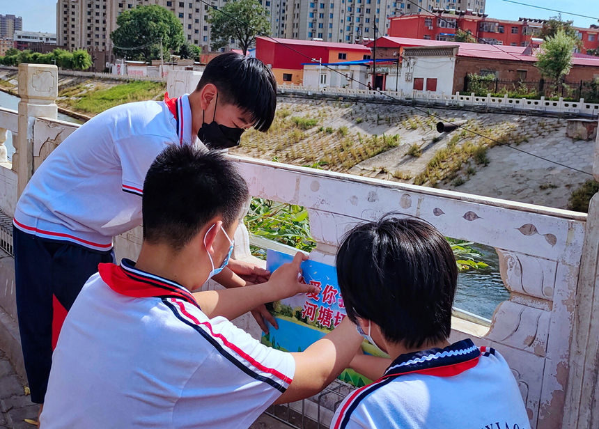 徐水小學(xué)學(xué)雷鋒志愿者在瀑河河邊張貼防溺水警示標語。 徐水區(qū)委宣傳部供圖