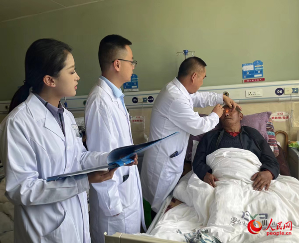 董光明（左三）帶領(lǐng)醫(yī)生對患者進(jìn)行術(shù)前檢查。人民網(wǎng)記者 杜燕飛攝