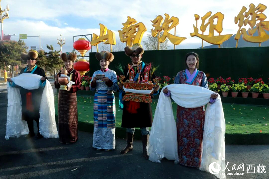扎西曲登社區(qū)的居民在“山南歡迎您”標(biāo)志前，手持潔白哈達和切瑪，列隊迎接來自區(qū)內(nèi)外的游客，用最隆重的禮儀開啟一場沉浸式藏歷新年民俗體驗之旅。人民網(wǎng)記者 吳雨仁攝
