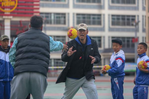 在高原上教孩子們打手球，“慢慢兒來(lái)，甭著急！”