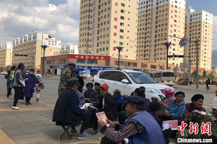 圖為會澤縣城易地扶貧搬遷安置點內，老人們聚在廣場上聊天，身后是他們的新家?！】姵?攝
