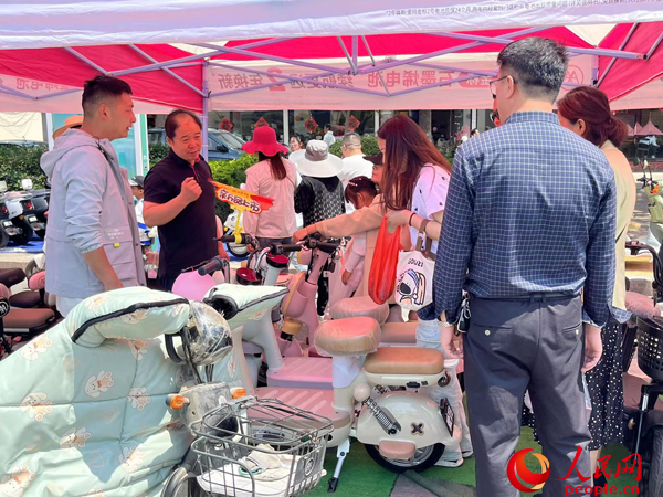 某電動自行車品牌工作人員向消費者介紹以舊換新相關(guān)情況。人民網(wǎng)記者 杜燕飛攝