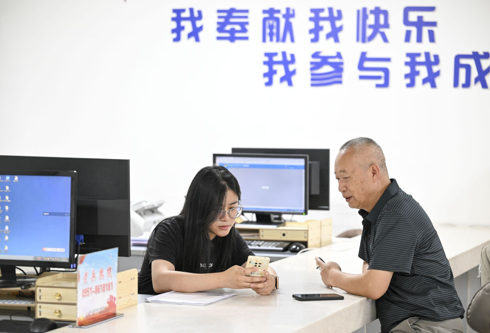 2024年6月20日，在寧夏銀川市金鳳區(qū)長城花園社區(qū)黨群服務(wù)中心，工作人員幫助居民辦理業(yè)務(wù)。圖片來源 新華社
