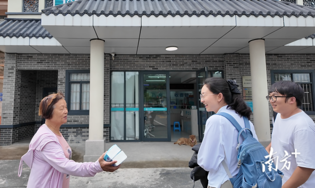 公共服務(wù)組成員王櫻潔（中）和張龍（右）在崖口村衛(wèi)生室前跟村民打招呼。