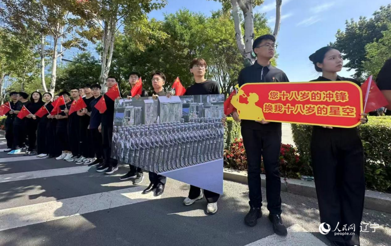 沈陽市人民廣場上，大學(xué)生們手持閱兵的圖片，告慰英烈。人民網(wǎng)記者 周頌雪攝