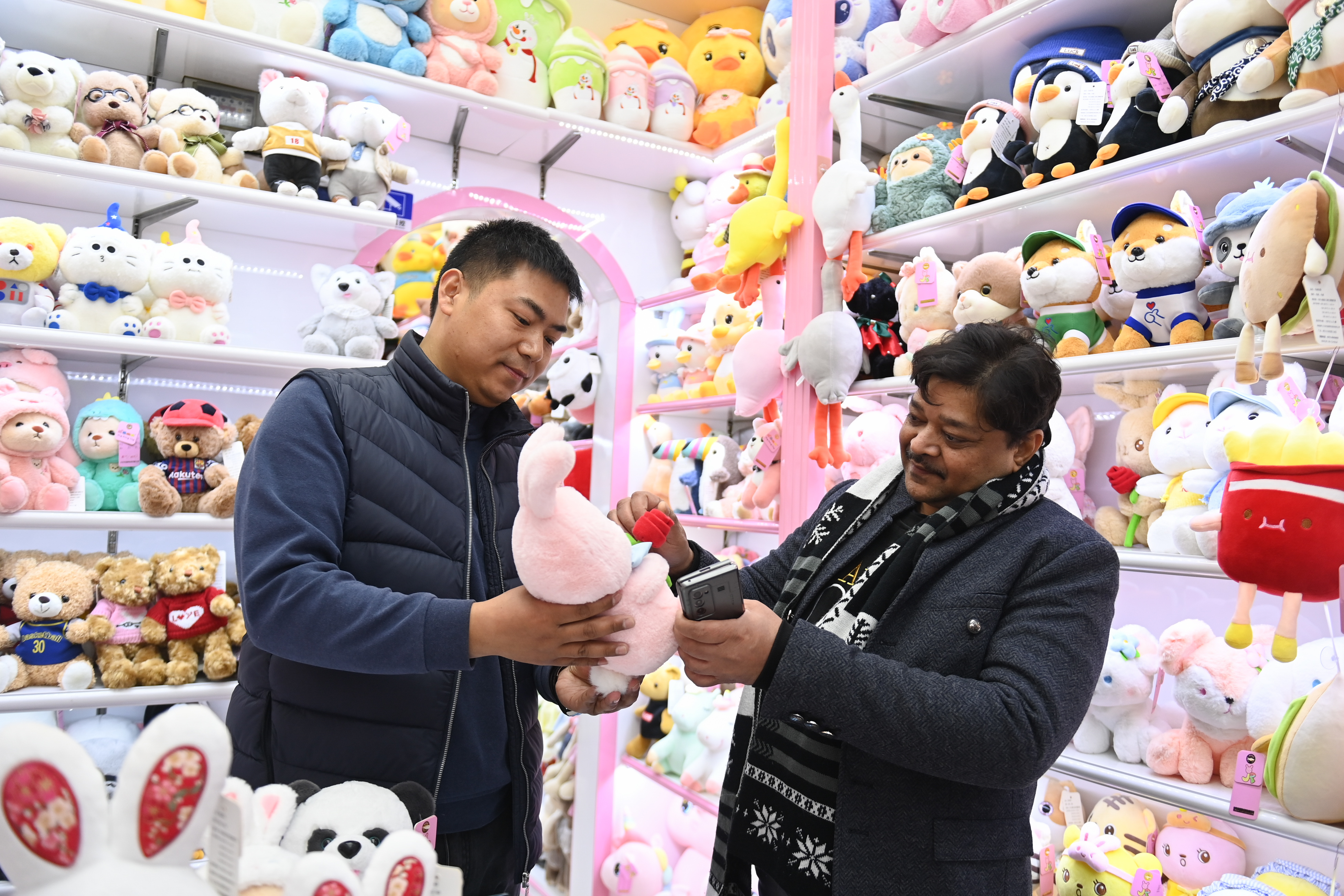 2023年2月2日，來自印度的客商（右）在義烏國際商貿(mào)城的一家玩具店鋪內(nèi)選購。