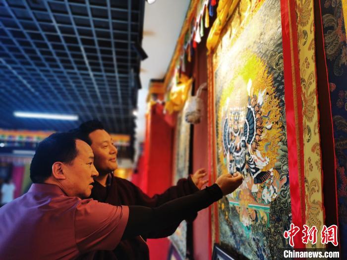 圖為久美尖措展示唐卡作品?！?zhí)砀?攝