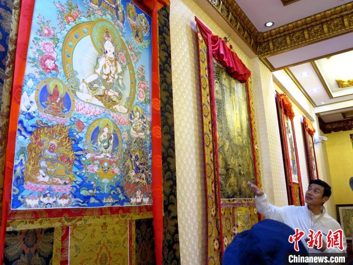圖為完德尖措展示熱貢龍樹(shù)畫(huà)苑內(nèi)的唐卡。　張?zhí)砀?攝