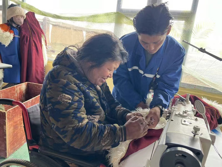 扎西奪爾登幫助殘疾員工裁剪。阿壩州文明辦供圖