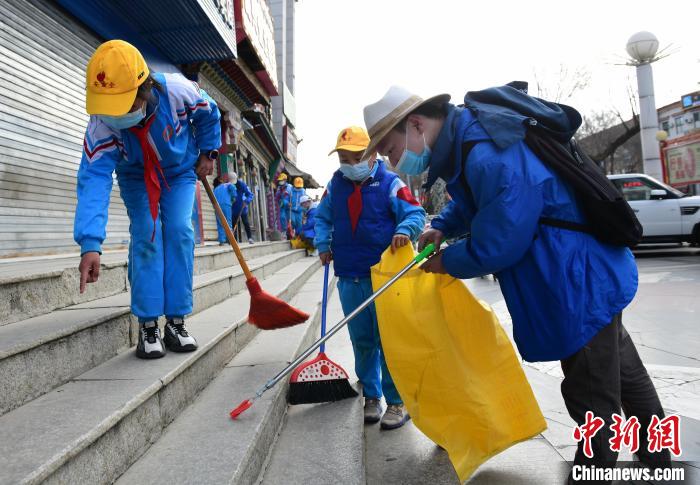 圖為拉薩市小學(xué)生打掃街道?！∝暩聛?lái)松 攝