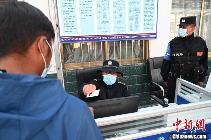 圖為移民管理警察登記完身份信息后將證件歸還給行人?！≮w朗 攝
