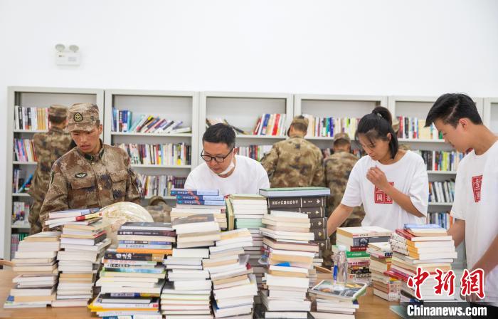 圖為志愿者們和邊防戰(zhàn)士整理圖書?！詵| 攝