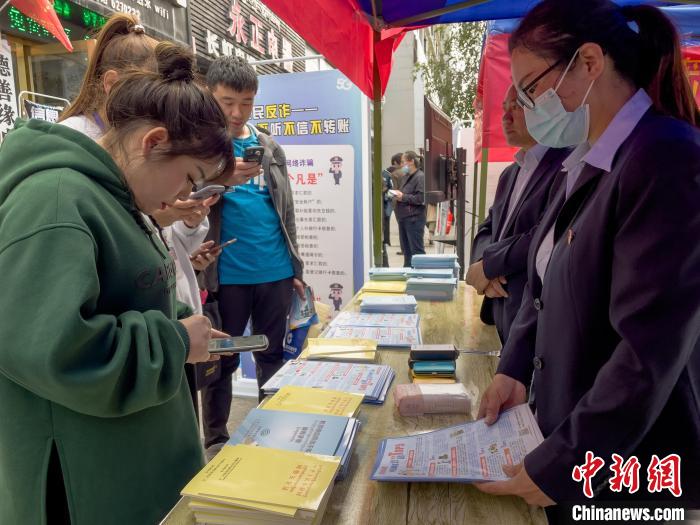 圖為工作人員正在向路過市民介紹國家反詐中心軟件的功能?！≈x牧 攝