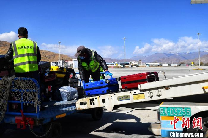 圖為機場工作人員傳送旅客行李箱?！≈芎?攝
