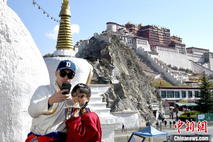 4月17日，游客身著藏式元素服裝在拉薩布達拉宮觀景臺拍照留念?！±盍?攝