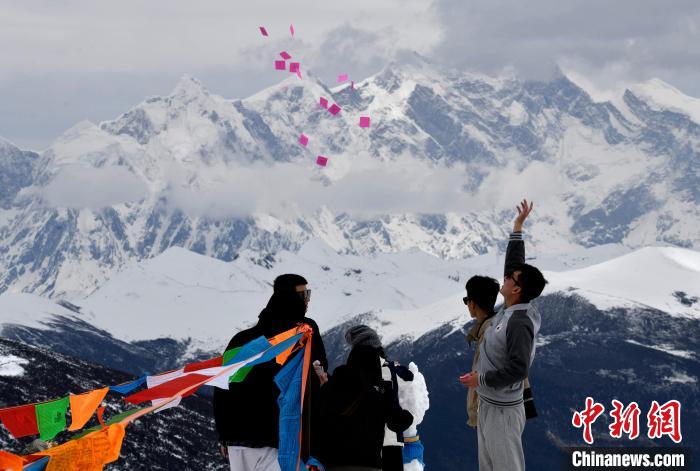圖為5月14日，游客在西藏林芝色季拉山觀景臺(tái)拋灑“隆達(dá)”(風(fēng)馬旗，藏族民眾的一種祈福方式)?！±盍?攝