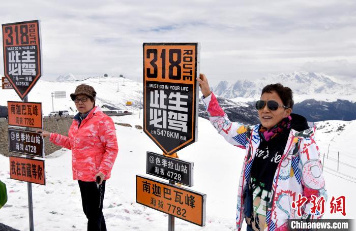 圖為5月14日，西藏林芝色季拉山觀景臺(tái)，游客與南迦巴瓦峰合影。　李林 攝