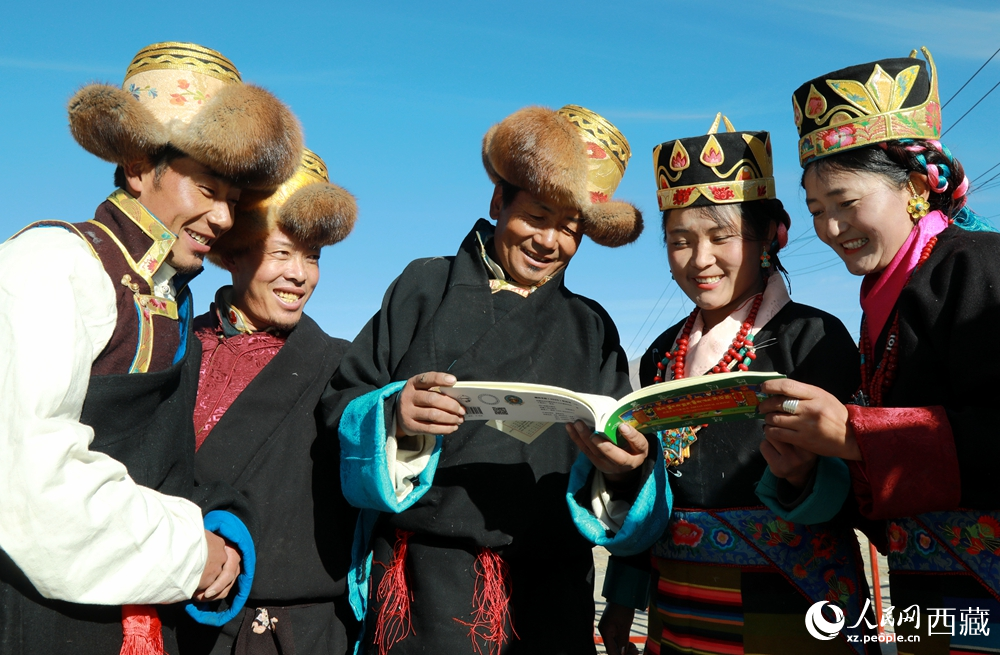 鄉(xiāng)親們身著民族盛裝，圍站在一起認(rèn)真翻看日歷，共話農(nóng)事安排與時節(jié)規(guī)律，笑容洋溢傳遞豐收期盼。人民網(wǎng)記者 吳雨仁攝