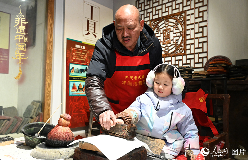 2025年1月27日，河南開封朱仙鎮(zhèn)木版年畫藝人尹國法指導(dǎo)小朋友研習(xí)年畫印制技藝。朱仙鎮(zhèn)木版年畫源自漢唐壁畫藝術(shù)，是中國木版年畫的鼻祖。2006年5月20日，朱仙鎮(zhèn)木版年畫經(jīng)國務(wù)院批準(zhǔn)列入第一批國家級(jí)非物質(zhì)文化遺產(chǎn)名錄。人民網(wǎng)記者 王玉興攝