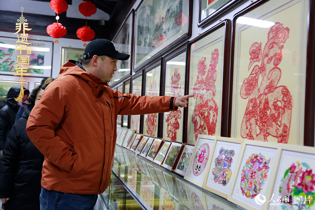 2025年1月23日，游客在天津楊柳青古鎮(zhèn)欣賞傳統(tǒng)剪紙作品，感受指尖上的古老藝術(shù)。人民網(wǎng)記者 崔新耀攝