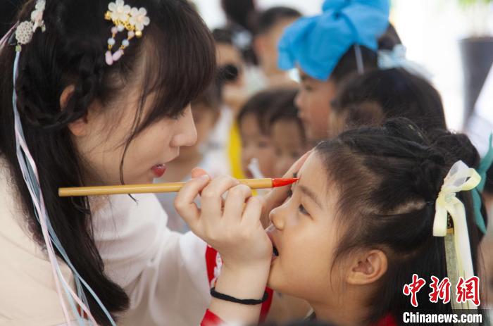 圖為老師在孩子們額頭上點(diǎn)上雄黃，驅(qū)邪辟禍?！《^生 攝