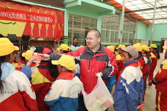 段玉平為孩子們分發(fā)愛心人士捐贈(zèng)的新華字典 圖片來(lái)源：央廣網(wǎng).jpg